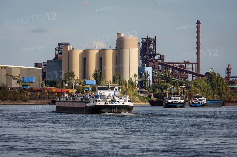 Duisburg, North Rhine-Westphalia, Germany, freighter at the southern harbour, Holcim cement works at the rear left, ThysseKrupp Steel blast furnace Schwelgern in Duisburg Marxloh at the rear right. Due to the draught, freighters can only navigate the Rhine with a small load and sometimes park in front of the entrance to Duisburg harbour due to the low water level, Europe