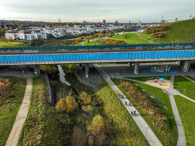 Dortmund, North Rhine-Westphalia, Germany, Phoenix Lake, in front the renaturalised Emscher under the B236 bridge. The river has been transformed into a near-natural body of water, flood protection and biodiversity through newly designed floodplains. A former industrial wasteland of 99 hectares was transformed into residential, work and leisure areas and 24 hectares of lake surface. In the event of heavy rainfall, the lake acts as a rainwater retention basin. Following the construction of a parallel sewer, the Emscher is now free of wastewater, having previously been an open, above-ground wastewater sewer, combined sewer with surface water and wastewater. The Phoenix Lake, a showcase project for structural change, is an artificial lake on the site of the former Phönix Ost steelworks in Dortmund's Hörde district, Europe