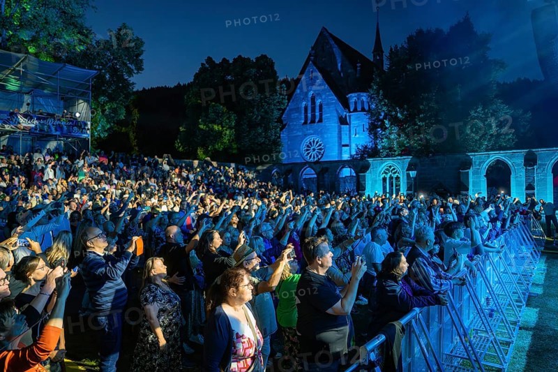 Large crowd at a night concert in front of a church, stage illuminated in blue, Klostersommer, Calw Hirsau, Black Forest, Germany, Europe
