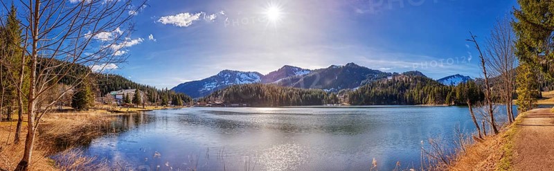 Large mountain lake with calm water surface, sunshine and picturesque mountain landscape, Spitzingsee