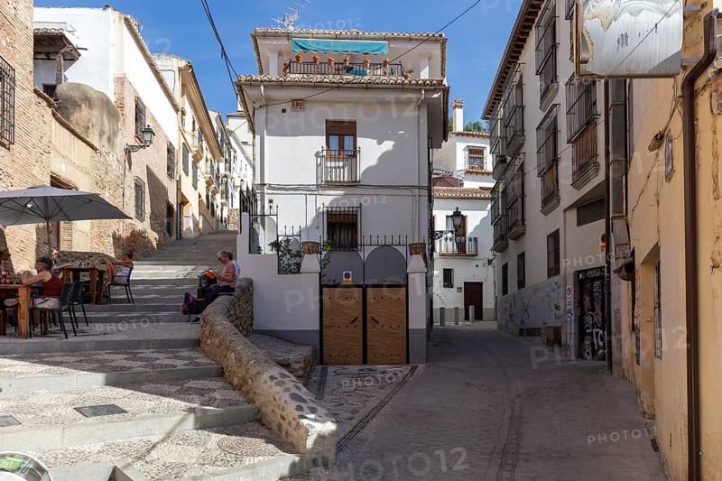 Sunny street with traditional buildings and a café, peaceful atmosphere, Granada