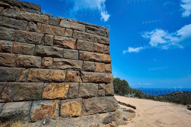 Ancient ruined wall in an arid landscape with a view of the sea and a clear blue sky, Palaiokastro, Ancient fortress, 3rd and 4th century BC, above Mandraki, Nisyros, Dodecanese, Greek Islands, Greece, Europe