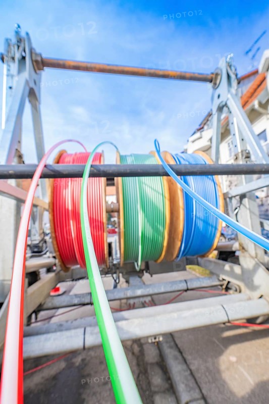 Coloured cables on a large reel in front of a building background, Wend Glasfasermontage during the jetting of conduits for fibre optic cables, Meßkirch, district of Sigmaringen, Germany, Europe
