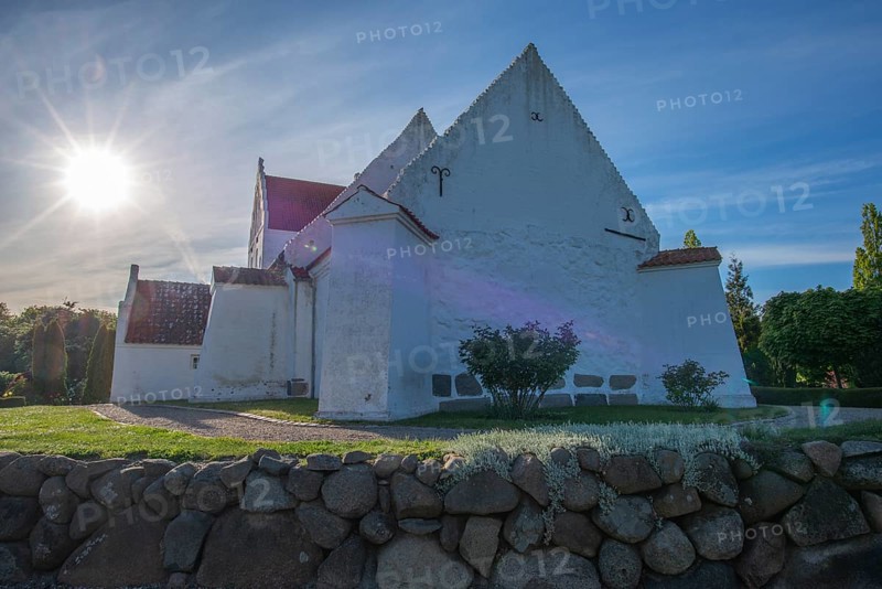 Whitewashed church in Dalby, backlight, stone wall made of boulders, Fyn, North Funen, Denmark, Europe