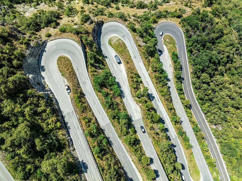 Mountain pass road with multiple hairpins, water pipeline, aerial view, drone shot. Valais, Switzerland, Europe
