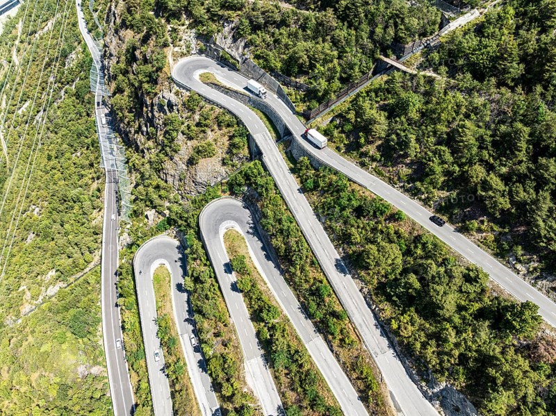 Mountain pass road with multiple hairpins, water pipeline, aerial view, drone shot. Valais, Switzerland, Europe