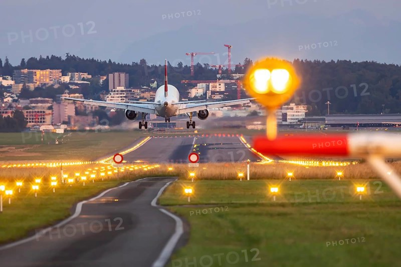 Aircraft of the airline Swiss landing in the evening with illuminated runway. Zurich Airport, Switzerland, Europe