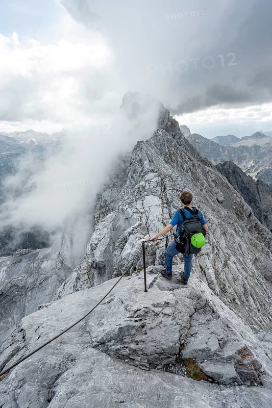 Mountaineer on a narrow rocky ridge on a steel cable, Watzmann crossing to Watzmann Mittelspitze, view of mountain panorama, Berchtesgaden National Park, Berchtesgaden Alps, Bavaria, Germany, Europe