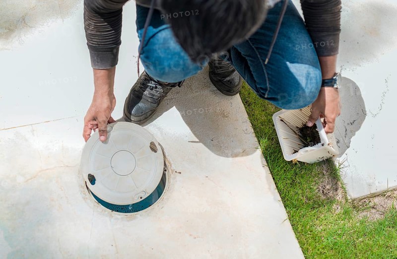 Cleaning and maintenance of the swimming pool skimmer basket. Person cleaning pool filter skimmer basket