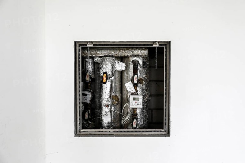 Insulated pipes and measuring device devices of a heating system can be seen behind a white wall, Berlin, 15.04.2024., Berlin, Berlin, Germany, Europe