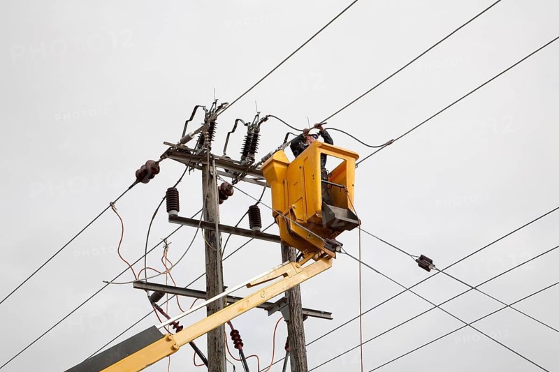 Electrician working in cherry picker connecting high voltage power lines at Bucklesham, Suffolk, England, United Kingdom, Europe