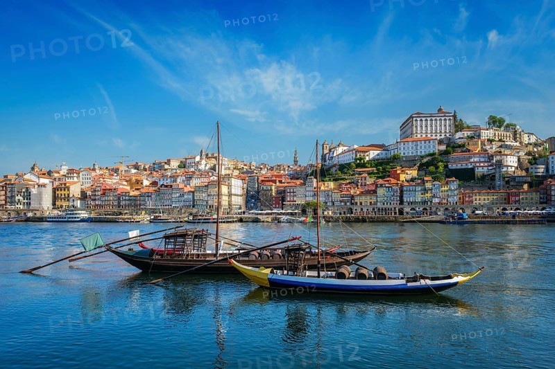 View of Porto city and Douro river with traditional boats with port wine barrels from famous tourist viewpoint Marginal de Gaia riverfront. Porto, Vila Nova de Gaia, Portugal, Europe