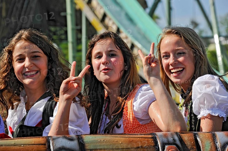 Three pretty funny girls in dirndls show Victoty sign, hand gesture V for Victory, victory, white water ride, ride at Oktoberfest, Wies'n, Wiesn, Munich, Upper Bavaria, Bavaria, Germany, Europe