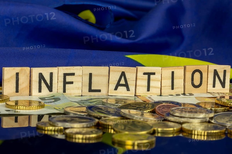 Symbolic image of inflation (in the euro area) : The word INFLATION in letter cubes on euro coins and banknotes