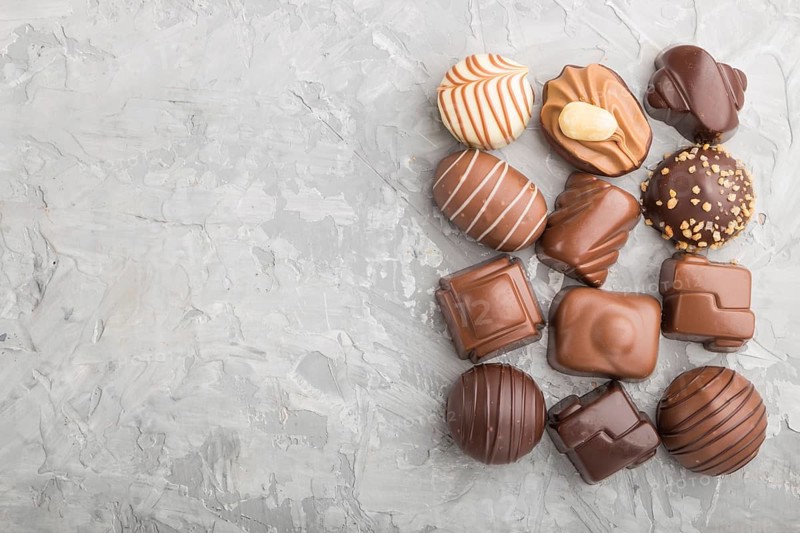 Different chocolate candies on a gray concrete background. top view, flat lay, copy space