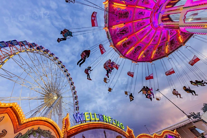 Chain carousel and Ferris wheel in the evening. 177th Cannstatter Volksfest at the Cannstatter Wasen. Bad Cannstatt, Stuttgart, Baden-Württemberg, Germany, Europe