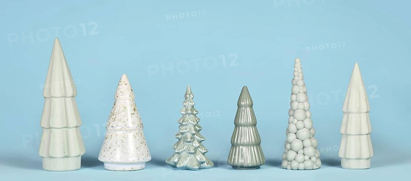 Banner with different shaped light green ceramic Christmas trees on blue background
