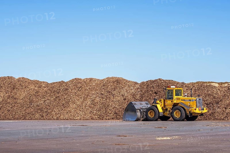 Loader at big stacks of wood chips for solid biomass fuel, Falköping, Sweden, Europe