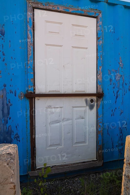 Blue painted metal building with white entrance door protected with steel bar, Quebec, Canada, North America