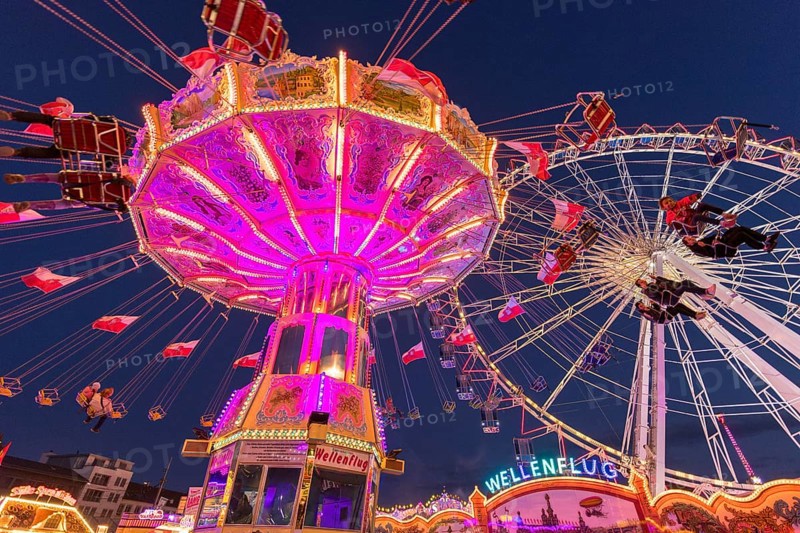 Illuminated carousel and Ferris wheel at night in a lively amusement park, funfair, wave flight, Cannstadter Volksfest, Stuttgart-Bad Cannstsdt, Baden-Württemberg