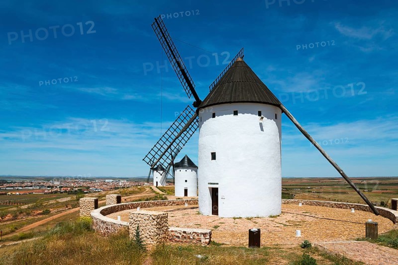 White windmills with black roofs in a wide landscape with paths under a blue sky, Alcazar de San Juan, Ciudad Real, Castilla-La Mancha, Route of Don Quixote, Spain, Europe