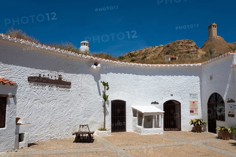 White courtyard with historic buildings and rustic ambience under a blue sky and mountains, museum, Cueva Museo, cave dwelling, cave district, Troglodytos, Barrio de Cuevas, Guadix, Granada province, Andalusia, Spain, Europe