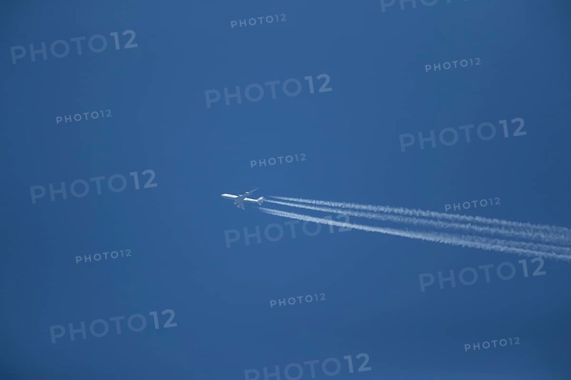 Boeing 747 aircraft of Lufthansa airlines flying across a blue sky leaving a contrail or vapor trail in the atmosphere behind the plane, England, United Kingdom, Europe