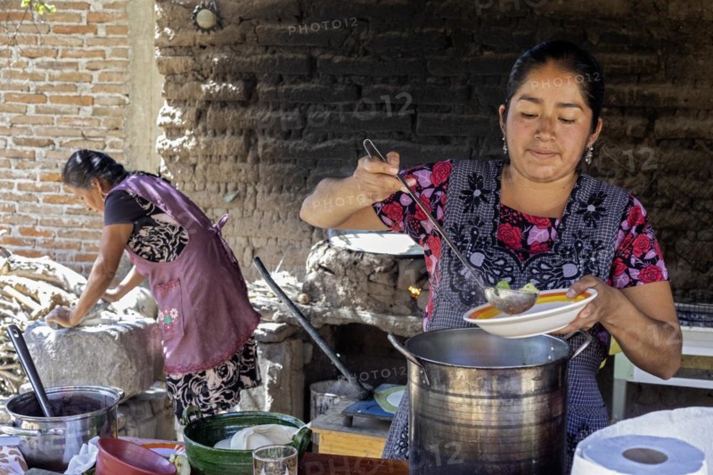 Teotitlan del Valle, Oaxaca, Mexico, Rural women in the Tlacolula Valley of Oaxaca benefit from a microfinance loan program run by the nonprofit En Via Foundation. Women can get interest-free loans starting at 1500 pesos ($75 US) to start or expand a business. The organization also gives classes in business basics, English, and internet marketing. Microloan recipient Brenda Martinez Gonzalez and her family prepare lunch for visitors who came to learn about the program, Central America