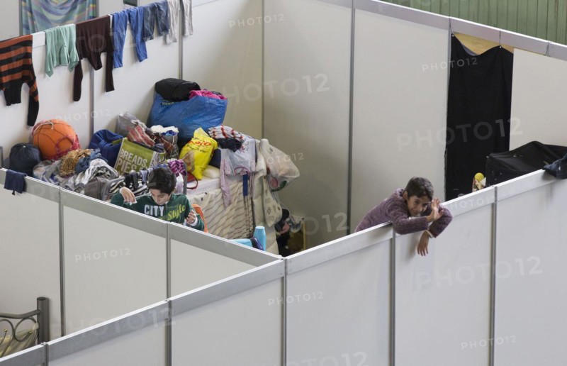 Children of refugees look over the wall of a temporary room in an emergency shelter for refugees on 9 December 2015 in the former hangar of Tempelhof Airport, Berlin, Berlin, Germany, Europe
