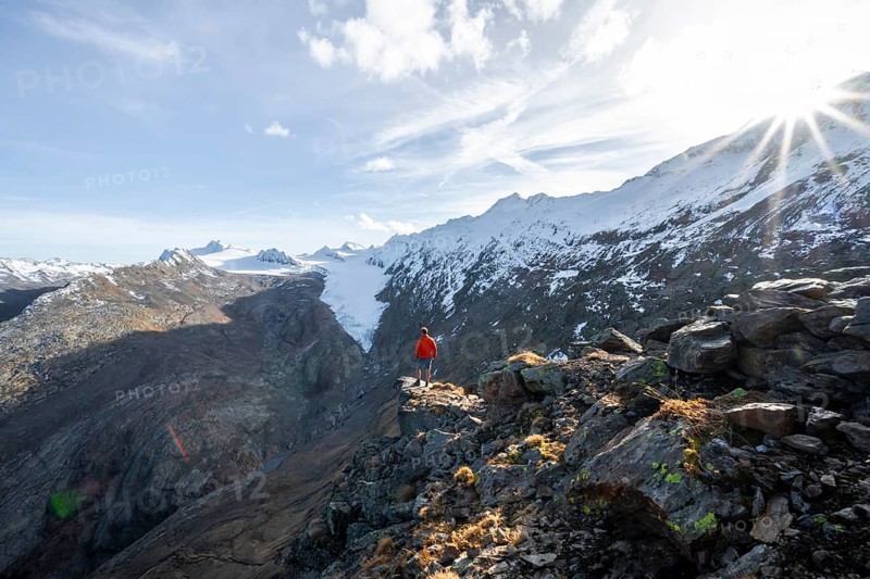 Mountaineer standing on a rock, surrounded by an impressive mountain landscape with snow-covered peaks in autumn View of Gurgler Ferner with summit Hochwilde and Falschungsspitze, Ötztal Alps, Tyrol, Austria, Europe