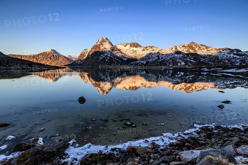 Fjord with steep snowy mountains, evening light, reflection, Flakstadoya, Lofoten, Norway, Europe
