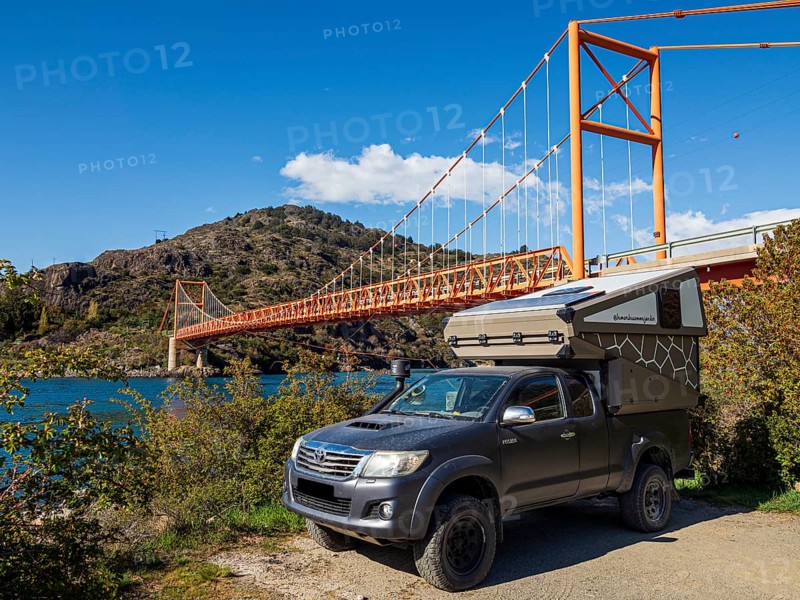 4x4 camper below famous orange suspension bridge Puente General Carrera, at lake Lago General Carrera, Patagonia, Chile, South America