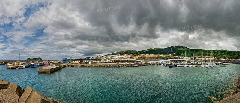 Coastal harbour with boats and houses surrounded by mountains under a cloudy sky, small town of Vila Franca do Campo, Sao Miguel, Azores, Portugal, Europe