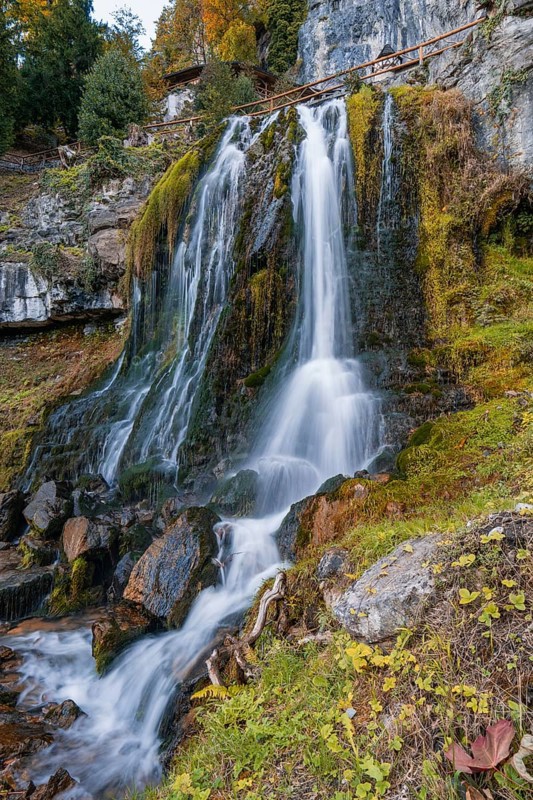 Lush waterfall flows over moss-covered rocks in autumnal surroundings, St. Beatus Caves, Switzerland, Europe