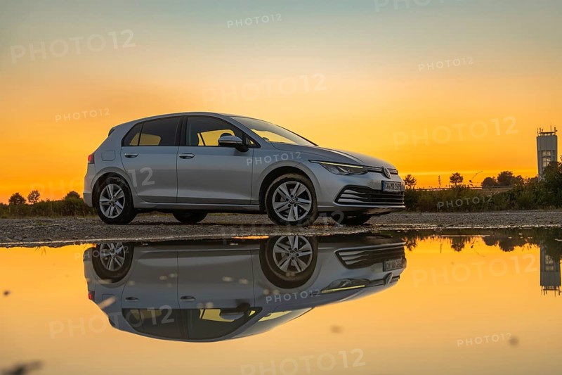 Silver car in setting sun, perfectly reflected in puddle, strong colours in the sky, VW Golff Diesel, Calw, Black Forest, Germany, Europe