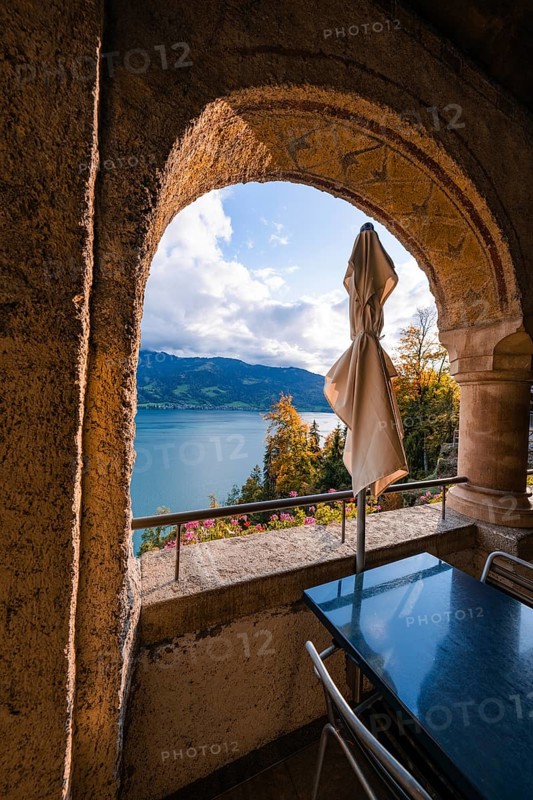 Looking through a stone arch onto a lake with mountains in the background, peaceful atmosphere, Beatus Caves, Switzerland, Europe