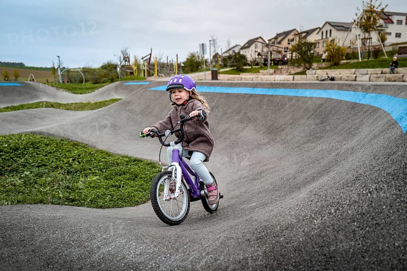 Child on pump track with bicycle helmet, riding bicycle on winding path on a cloudy autumn day, Stuttgart, Baden-Württemberg, Germany, Europe