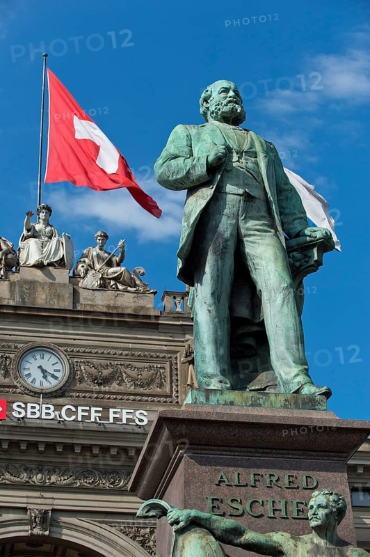 Swiss flag behind monument to Alfred Escher, Swiss politician, business leader and railway pioneer, by Richard Kissling, Bahnhofplatz central railway station, Zurich, Canton of Zurich, Switzerland, Europe