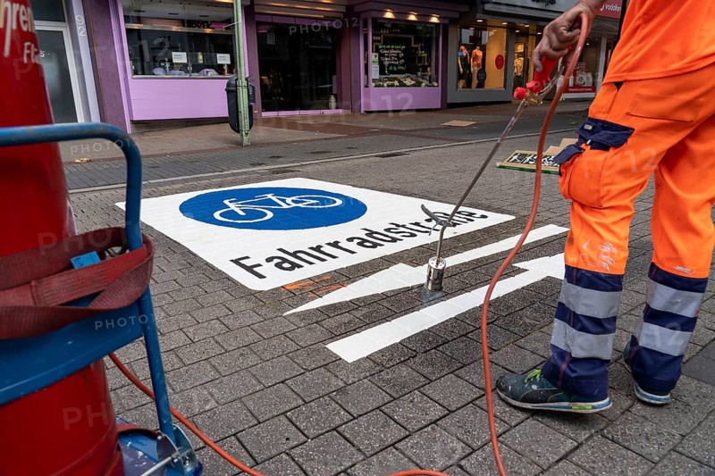 Application of road markings for a cycle lane, Rüttenscheider Straße in Essen, in the shopping and gastronomy district, cyclists have right of way over motorised vehicles, part of a cycle axis through Essen's city centre
