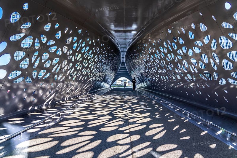 Light effects from the sun in the Parkbruk, a cycle and pedestrian bridge in the city centre of Antwerp, spanning a multi-lane city centre road with tram lines, and thus connecting two lively city districts Kop Spoor Noord and Eilandje, Belgium, without any crossings, Europe