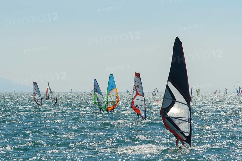 People windsurfing on a sunny day with clear blue skies and mountain backdrop, Lake garda, Torbole, Lake garda, Lago di Garda, Trentino, Italy, Europe