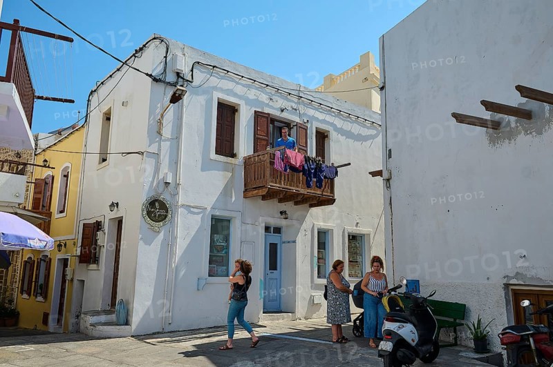 People standing outside an old white building with a balcony, laundry hanging outside, Mandraki, Nisyros, Dodecanese, Greek Islands, Greece, Europe