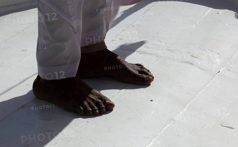 Brown feet standing on a white background, sailing ship