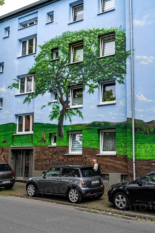 Residential buildings on Feldsieper Straße in Bochum, after an energy-efficient refurbishment, with facade insulation, the Bochumer Wohnstätten Wohnungsgenossenschaft had the buildings painted with a large mural by Dortmund graffiti artist Denis Klatt, it shows a bluethroat and a landscape with trees, life below ground and lots of sky on the entire facade, Bochum-Hamme, North Rhine-Westphalia, Germany, Europe