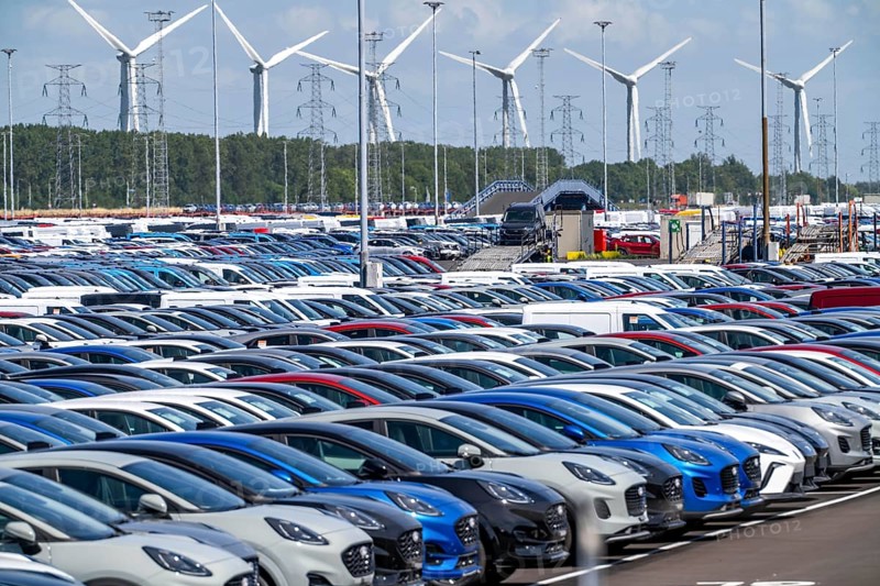 Storage area for new cars in the port of Vlissingen-Oost, vehicles are temporarily stored on over 100 hectares to ship them from Europe to the United Kingdom, Ford cars, others such as models from the Chinese car manufacturer BYD are delivered from here in Europe, wind farm, Netherlands