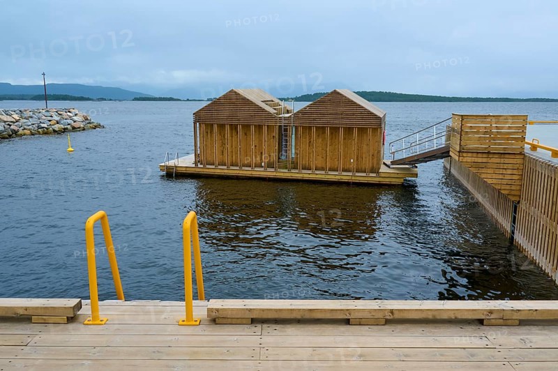 Outdoor sea pool by the fjord with small wooden sauna huts, overcast sky and calm water, Molde, Romsdal, Norway, Europe