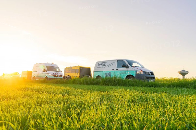 Transport vehicles on a green meadow at sunset with a clear sky, glass fibre installation, Calw district, Black Forest, Germany, Europe