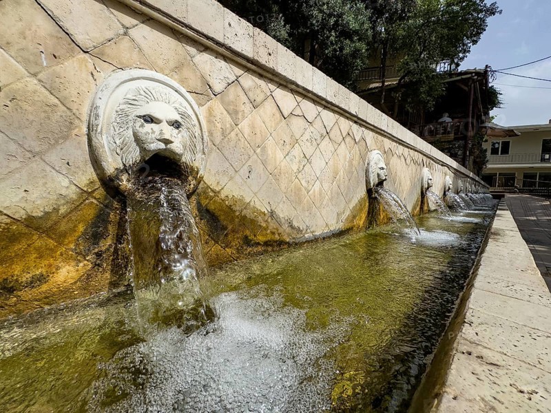 Partial view of lion fountain Venetian fountain Kefalovrisi on the main square of Spili village, large gargoyle in the form of a lion's head on the left, lion's head below collecting basin for drinking water, Spili, Crete, Greece, Europe
