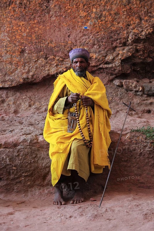 Rock churches of Lalibela, pilgrim prays with a rosary in front of a rock church, Ethiopia, Africa