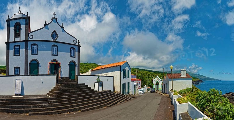 White church Igreja de São João Baptista on the village square in coastal location with clear sky in the background, São João, Pico Island, Azores, Portugal, Europe